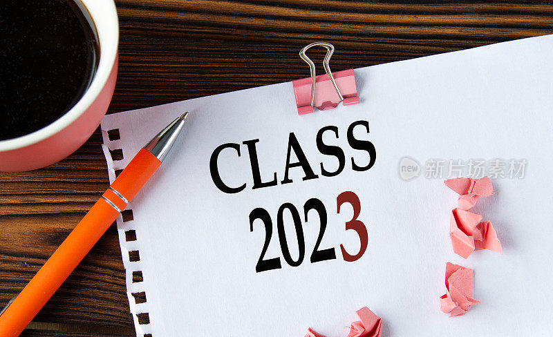 班级2023 -单词在一个白色的纸上，一个木制的棕色背景，一杯咖啡和一支笔